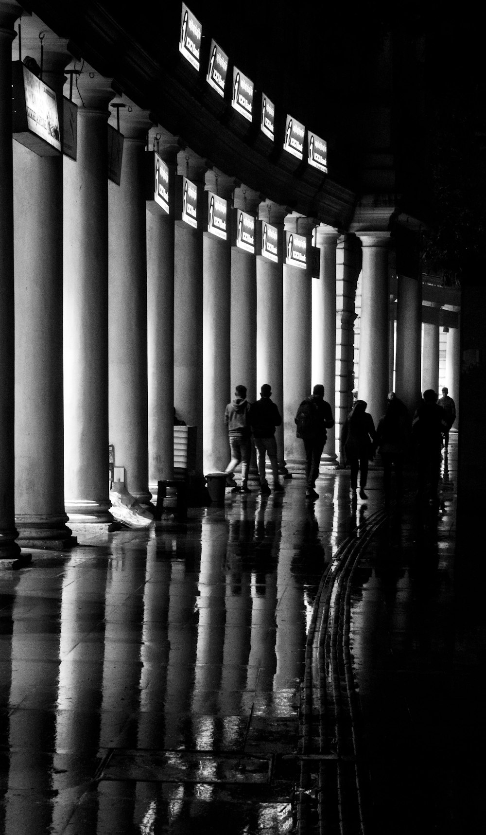 a black and white photo of people walking in the rain