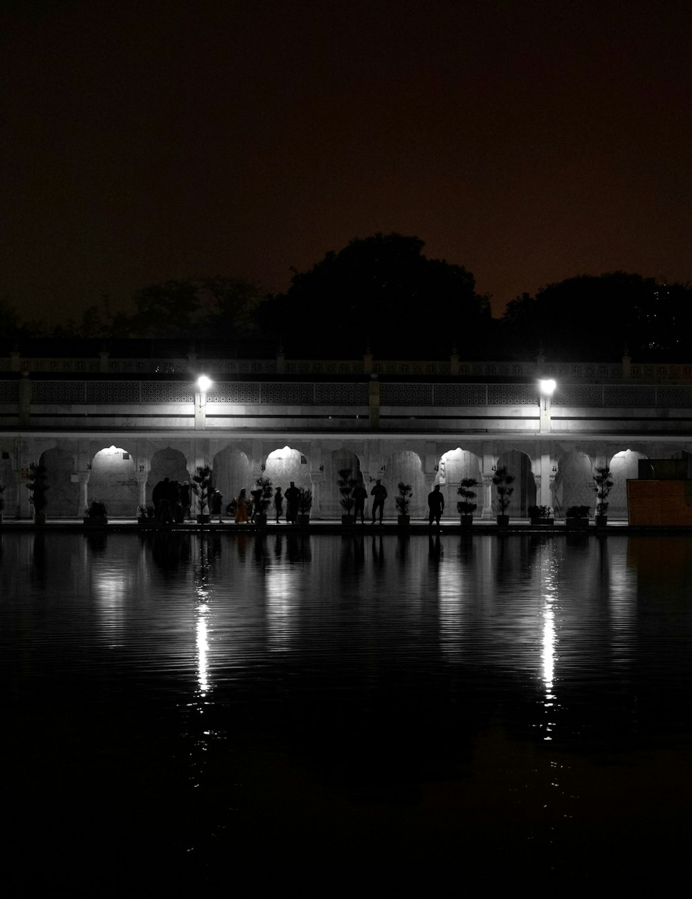 a group of people standing around a lake at night