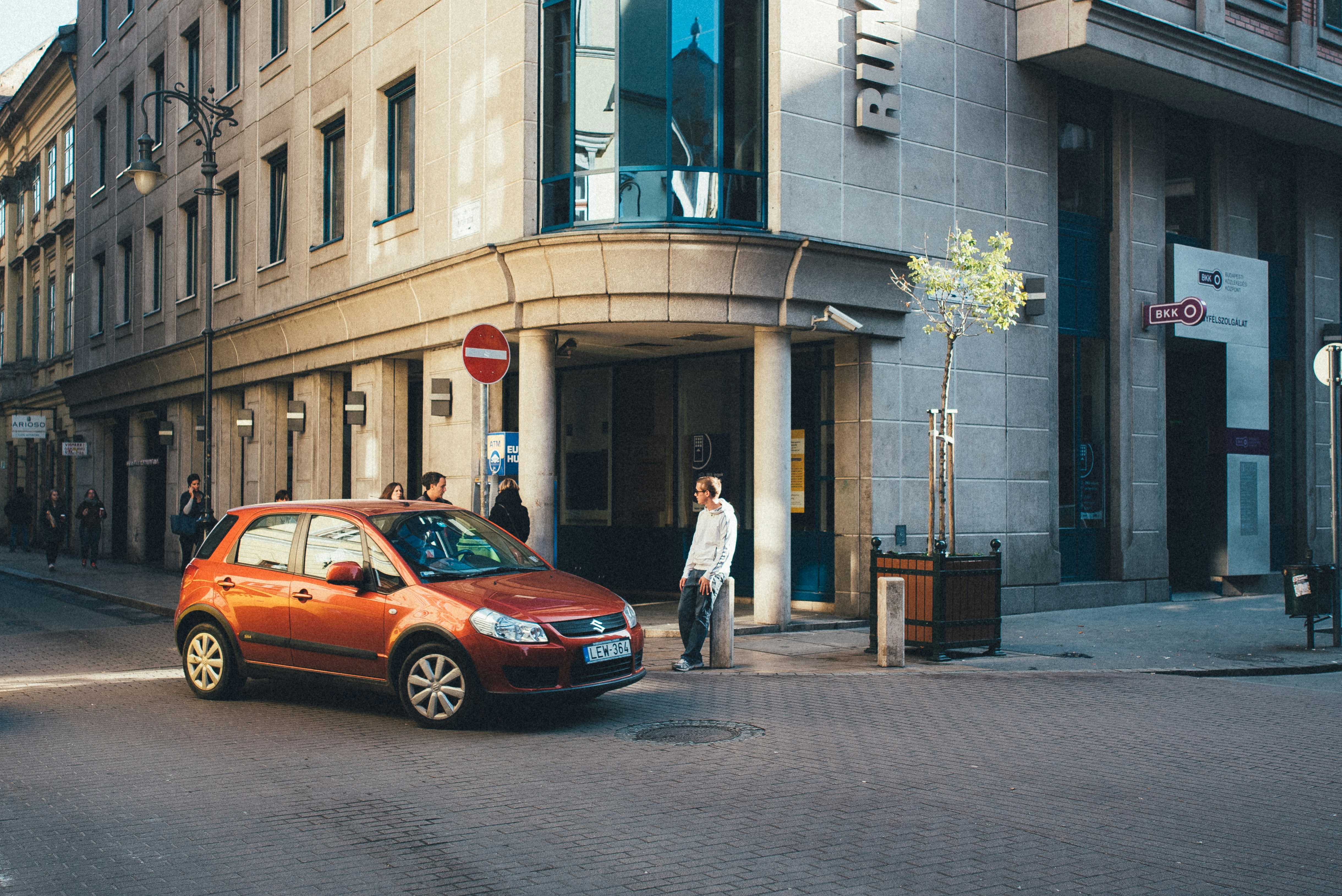 a small orange car parked in front of a tall building