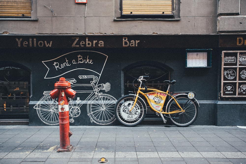 a yellow bike parked next to a red fire hydrant