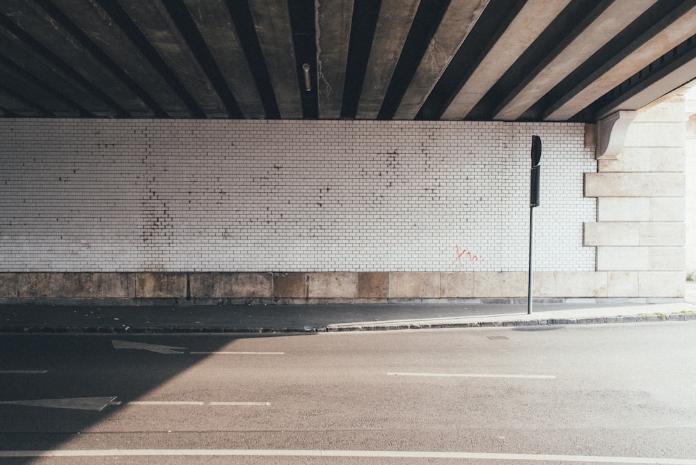 an empty parking lot with a white brick wall