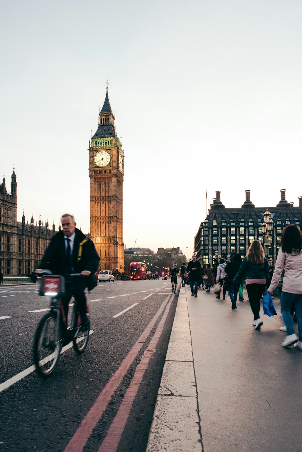 a man riding a bike down a street next to a tall clock tower