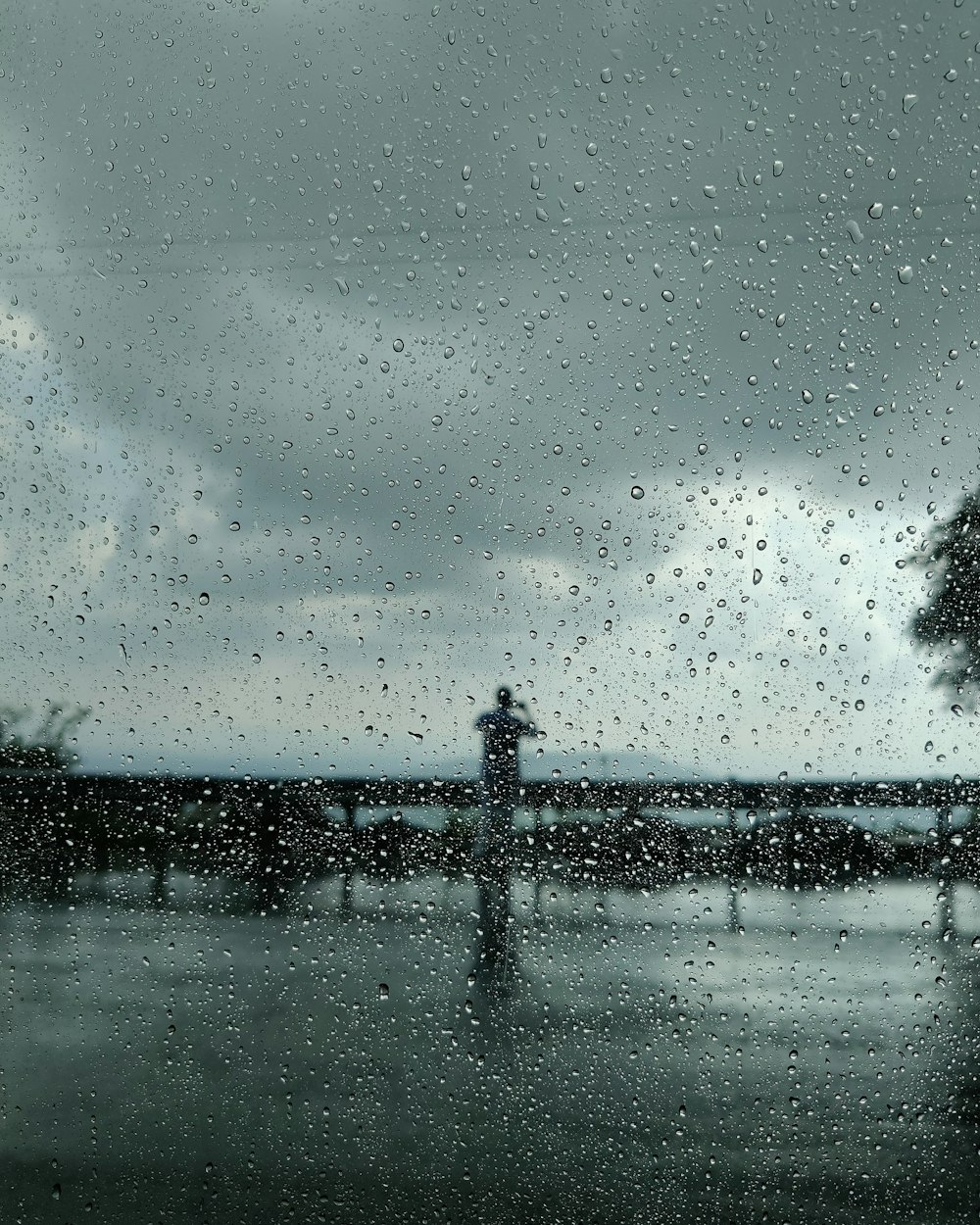 a person standing on a bridge in the rain