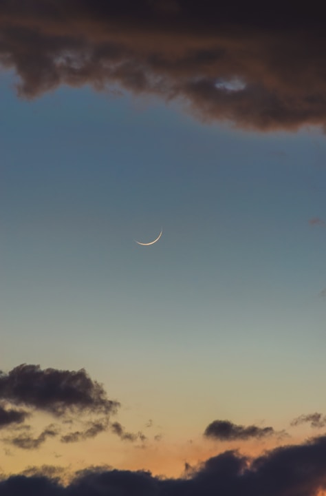 the moon is seen through the clouds in the sky
