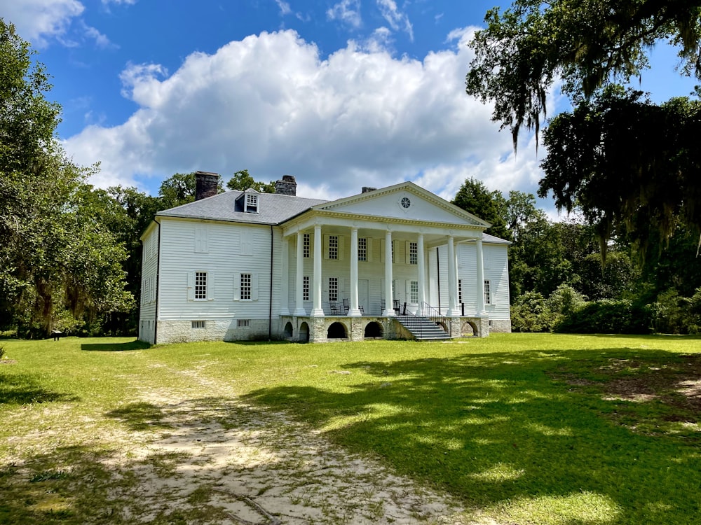 a large white house sitting on top of a lush green field