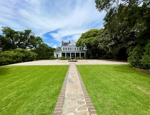 a large white house sitting on top of a lush green field