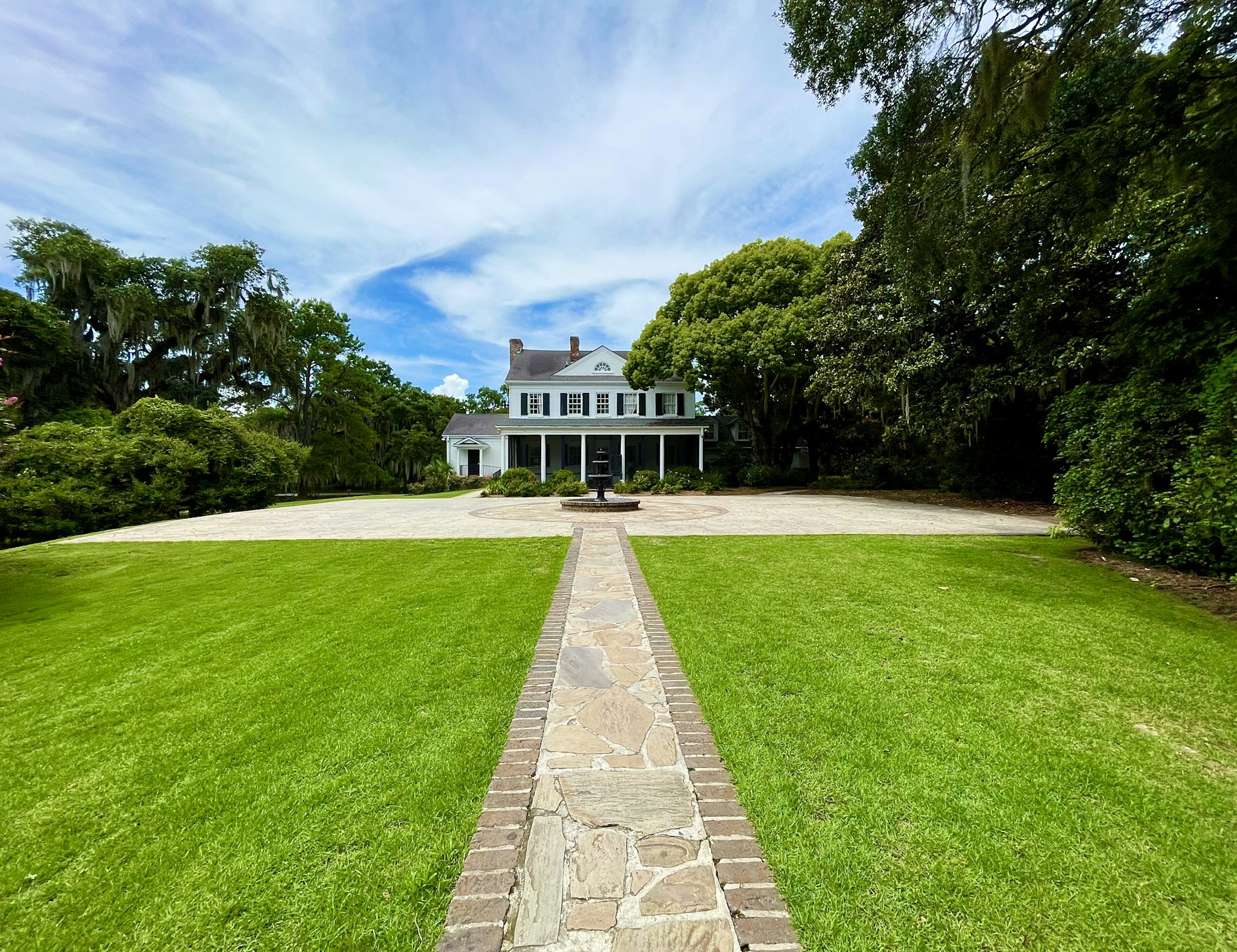 a large white house sitting on top of a lush green field