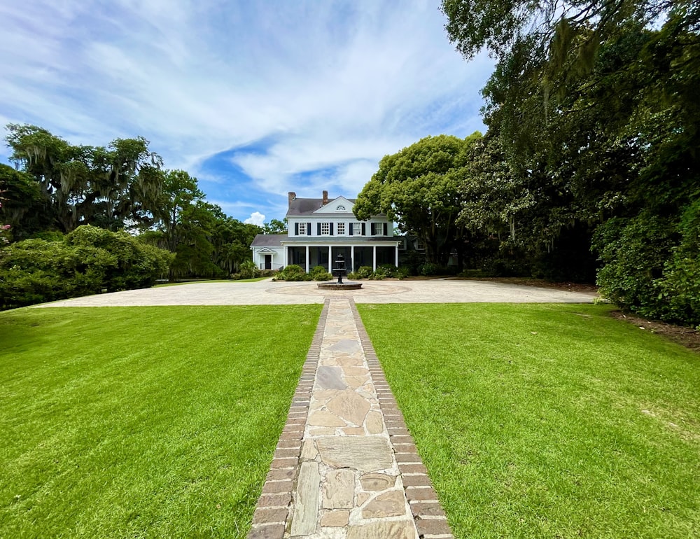 a large white house sitting on top of a lush green field