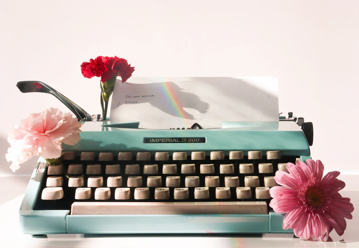 A pink flower sitting on top of a blue typewriter