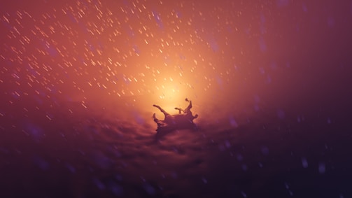 A dramatic scene featuring a silhouetted figure falling through a glowing and swirling atmospheric environment. The background is filled with vibrant orange and purple hues, reminiscent of a fiery or mystical setting. Particles or sparks seem to float around, enhancing the dynamic and surreal nature of the scene.