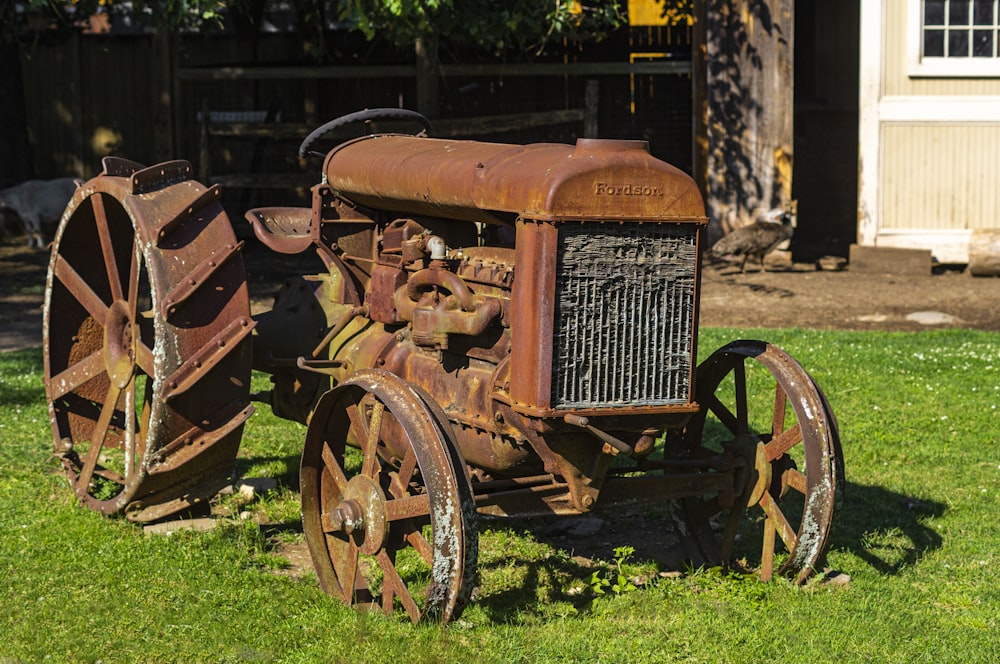 an old rusty tractor sitting in the grass