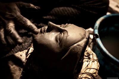 An artist’s hands shaping a fresh mask, highlighting the raw, imperfect textures.