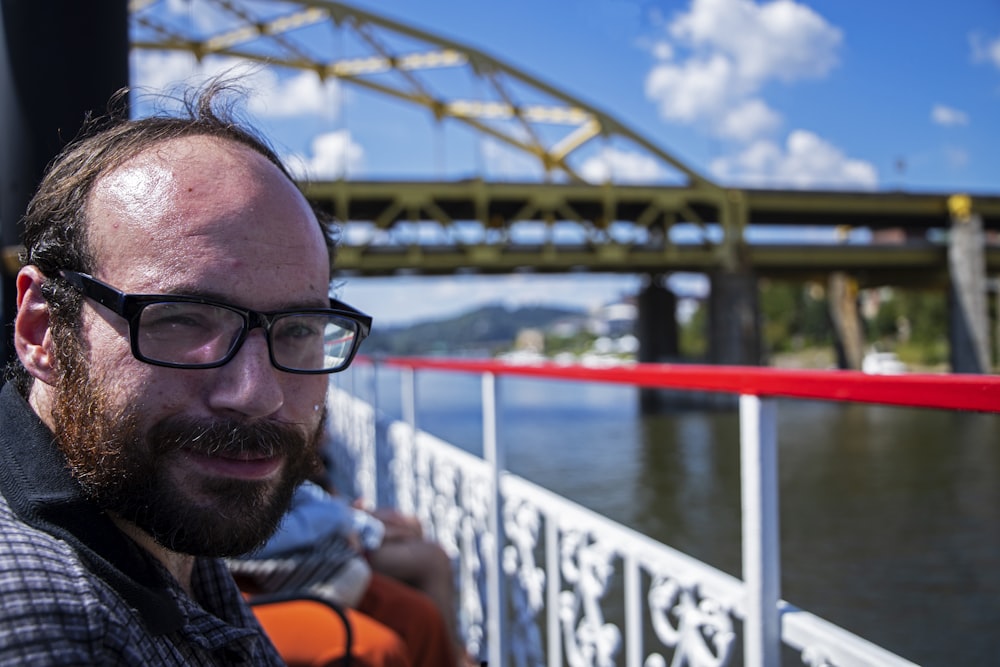 a man with a beard and glasses on a boat