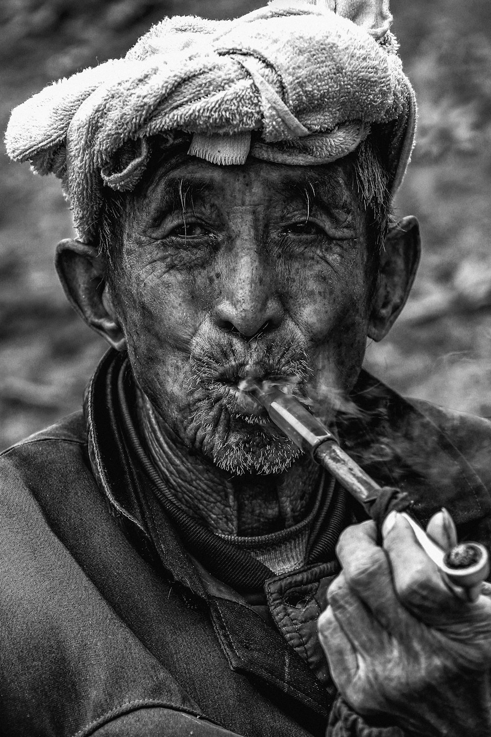 a black and white photo of a man smoking a pipe