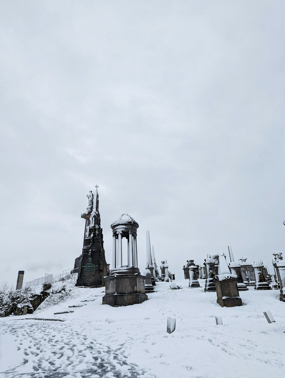 Un cementerio cubierto de nieve con una torre del reloj al fondo