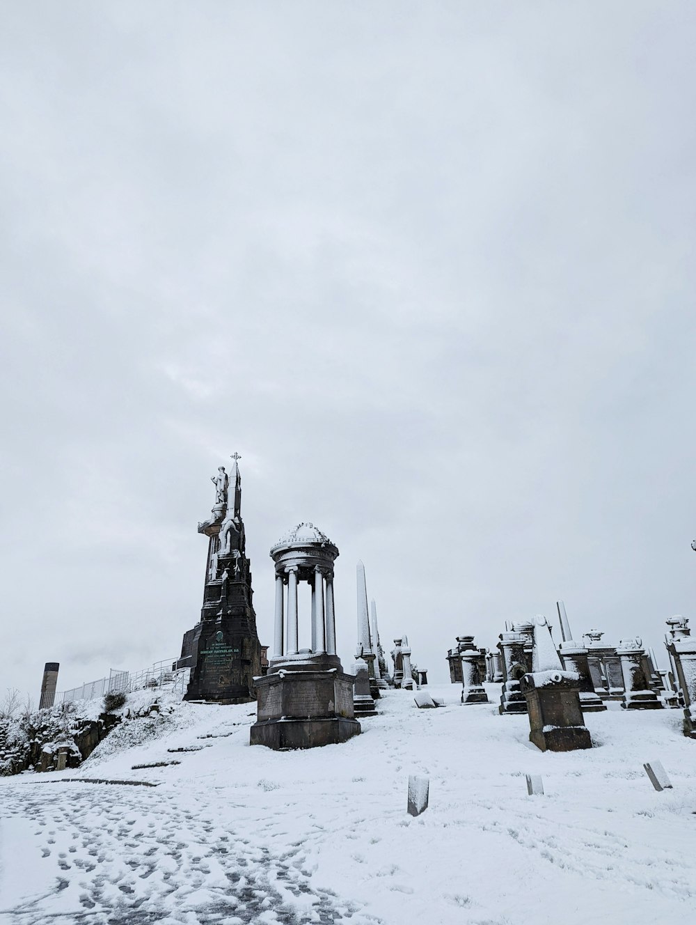 a snow covered cemetery with a clock tower in the background