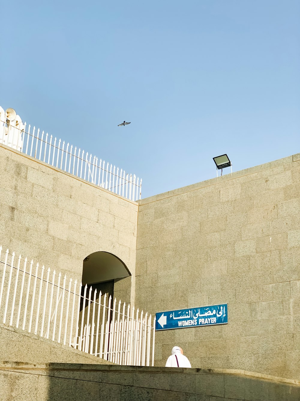 an airplane flying over a building with a white fence