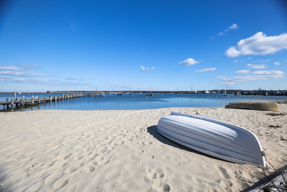 a white boat sitting on top of a sandy beach