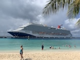 a cruise ship docked at a beach with people swimming in the water