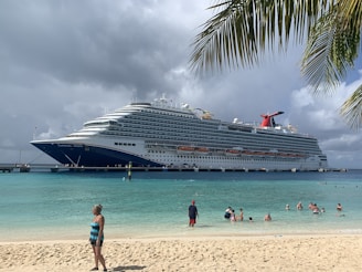 a cruise ship docked at a beach with people swimming in the water