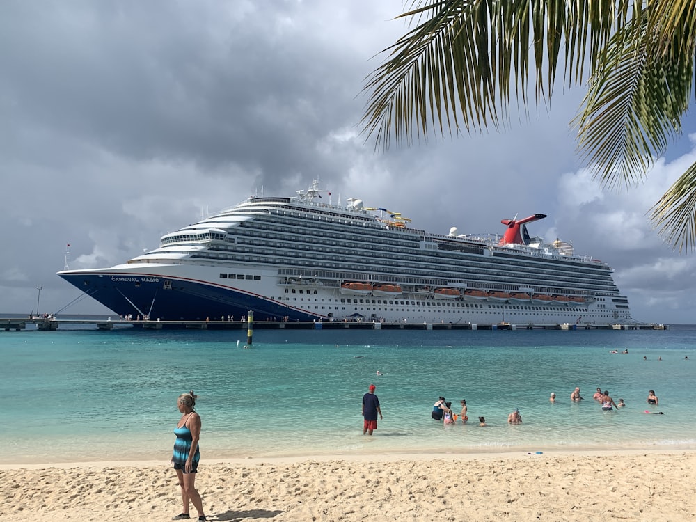 a cruise ship docked at a beach with people swimming in the water