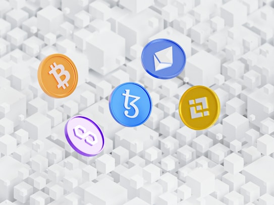 Five cryptocurrency symbols are depicted as coins with distinct logos floating above a pattern of white 3D cubes. The coins represent Bitcoin, Ethereum, Tezos, Polygon, and Binance Coin.