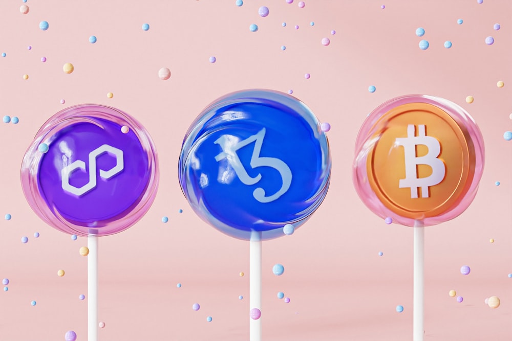 three lollipops with bitcoin on them on a pink background