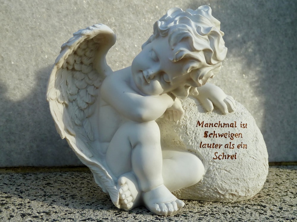 Una statua di un angelo seduto sulla cima di una roccia foto –  Südwestfriedhof Immagine gratuita su Unsplash