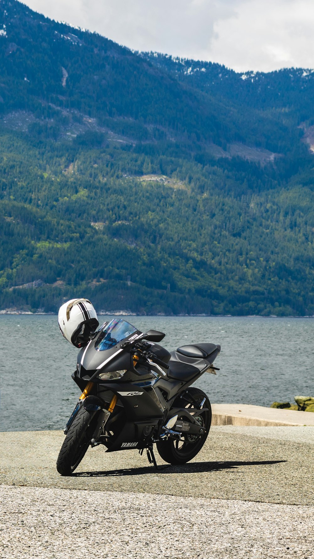 A motorcycle parked on the side of a road next to a body of water