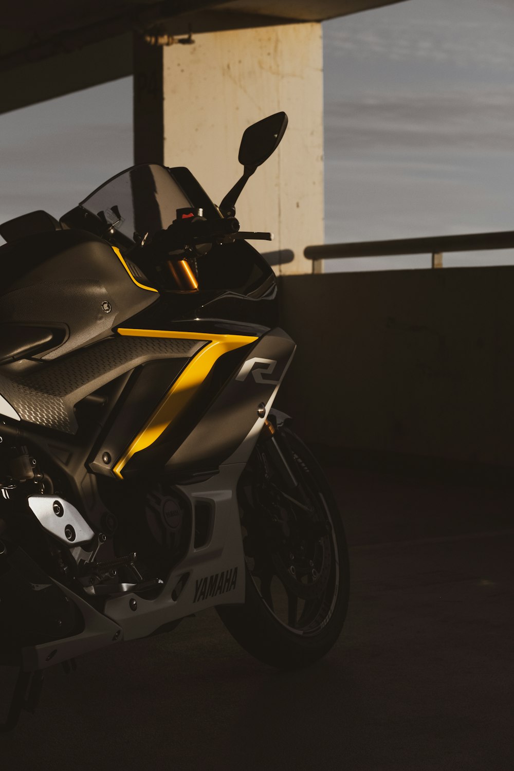 a black and yellow motorcycle parked under a bridge