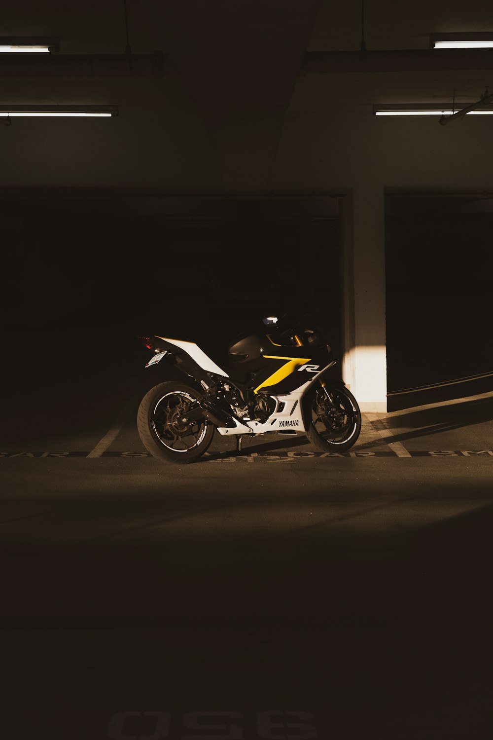 a yellow and white motorcycle parked in a parking garage