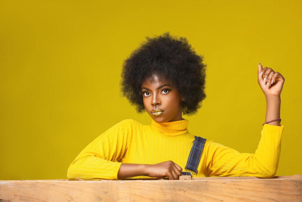 a woman in a yellow sweater holding a cell phone