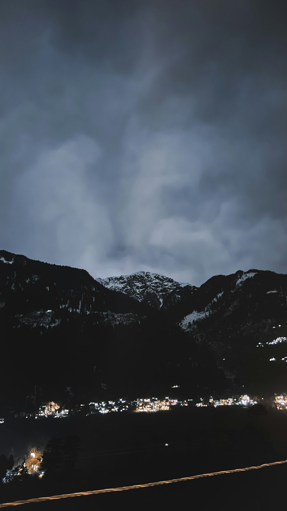 a mountain covered in snow at night with a cloudy sky