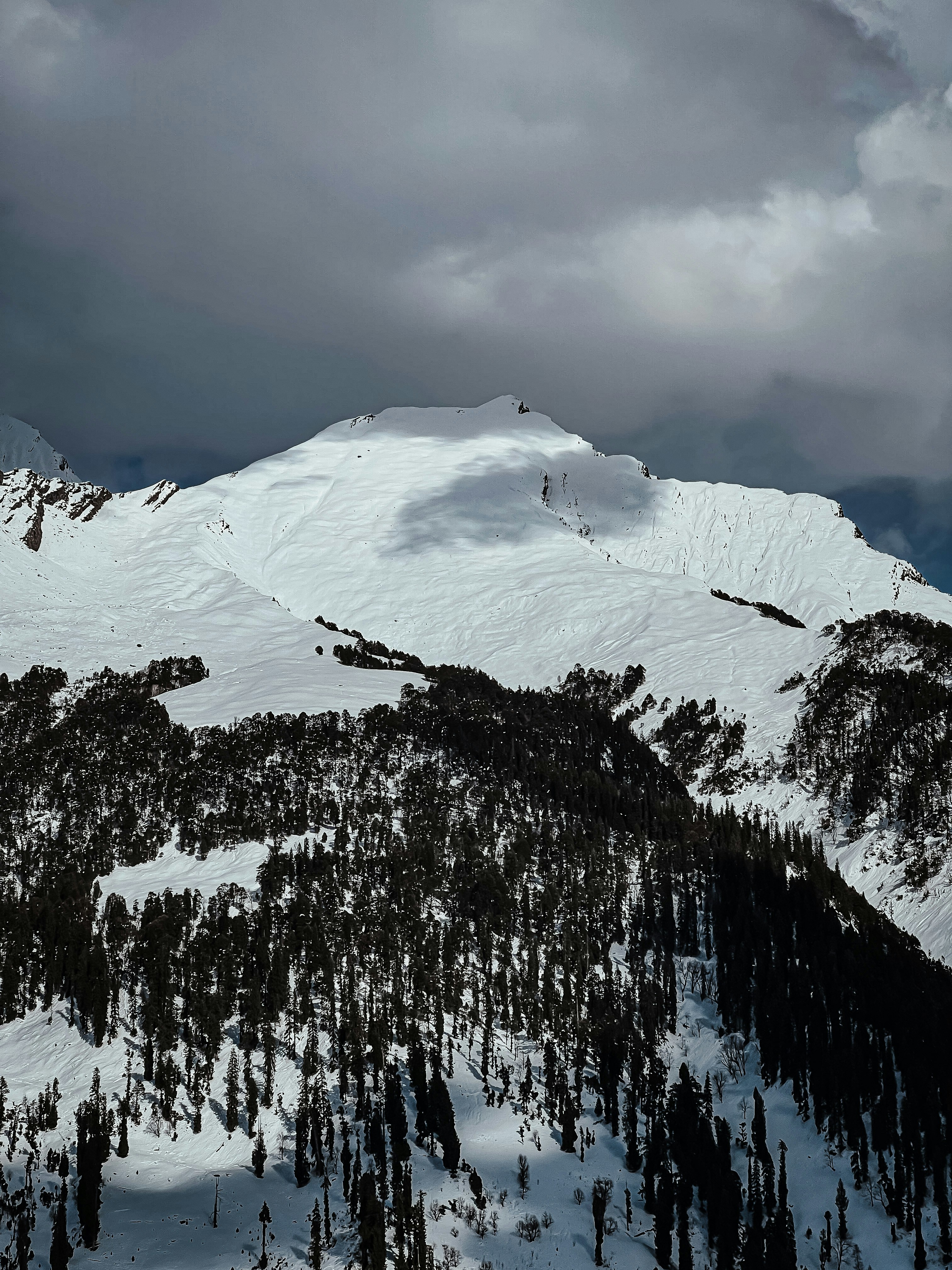 a mountain covered in snow under a cloudy sky