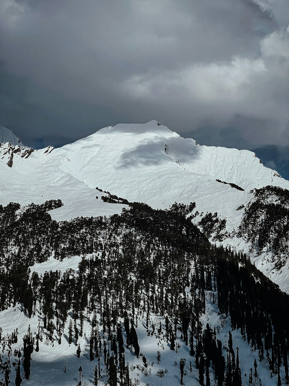 a mountain covered in snow under a cloudy sky