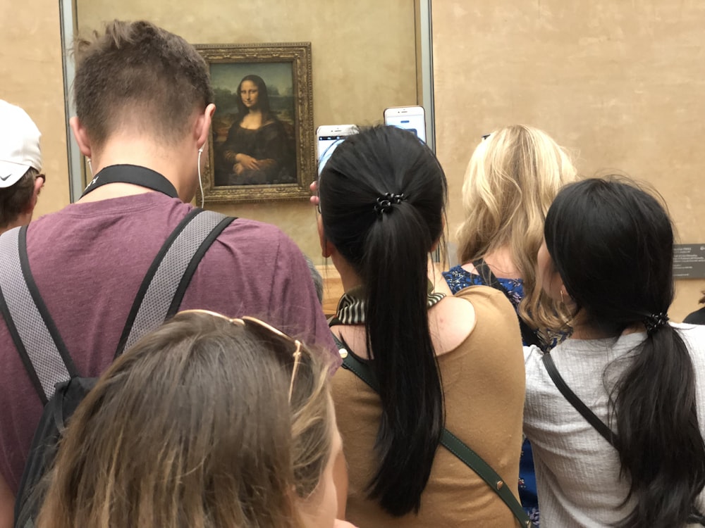 um grupo de pessoas em pé na frente de uma pintura