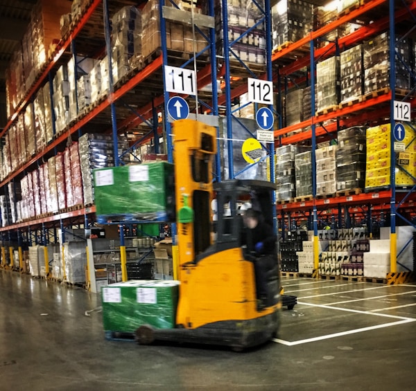 a forklift driving through a warehouse filled with pallets