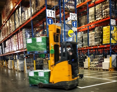 a forklift driving through a warehouse filled with pallets