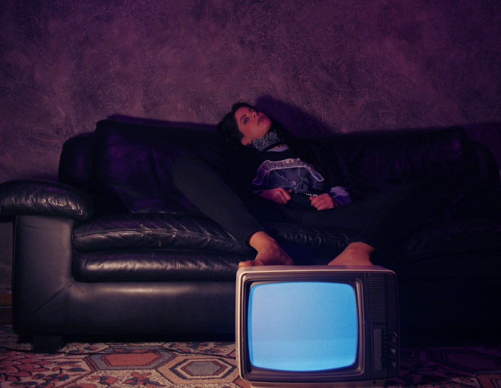 a woman sitting on a couch next to a tv