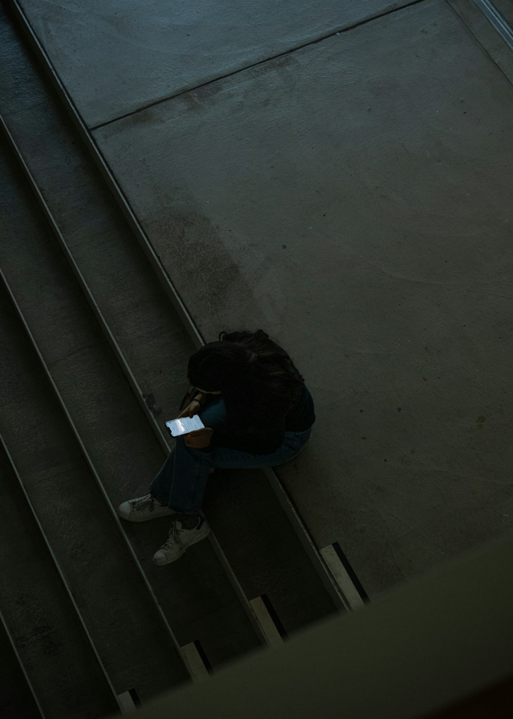 uma pessoa sentada no chão usando um telefone celular