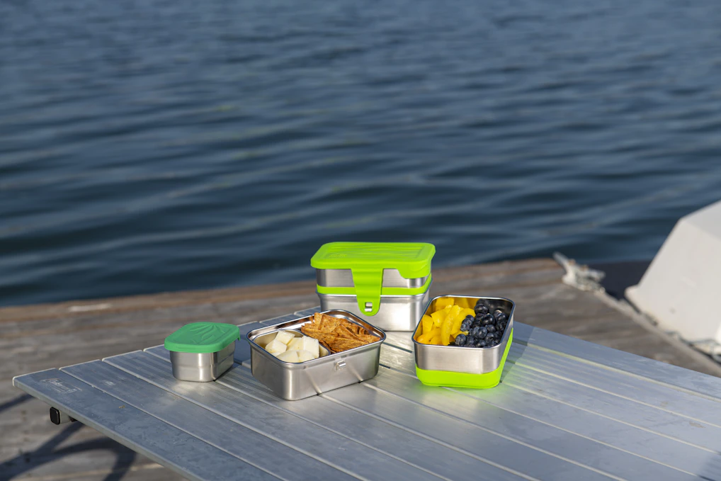 A colorful assortment of lunch containers and storage sets arranged neatly on a wooden table.