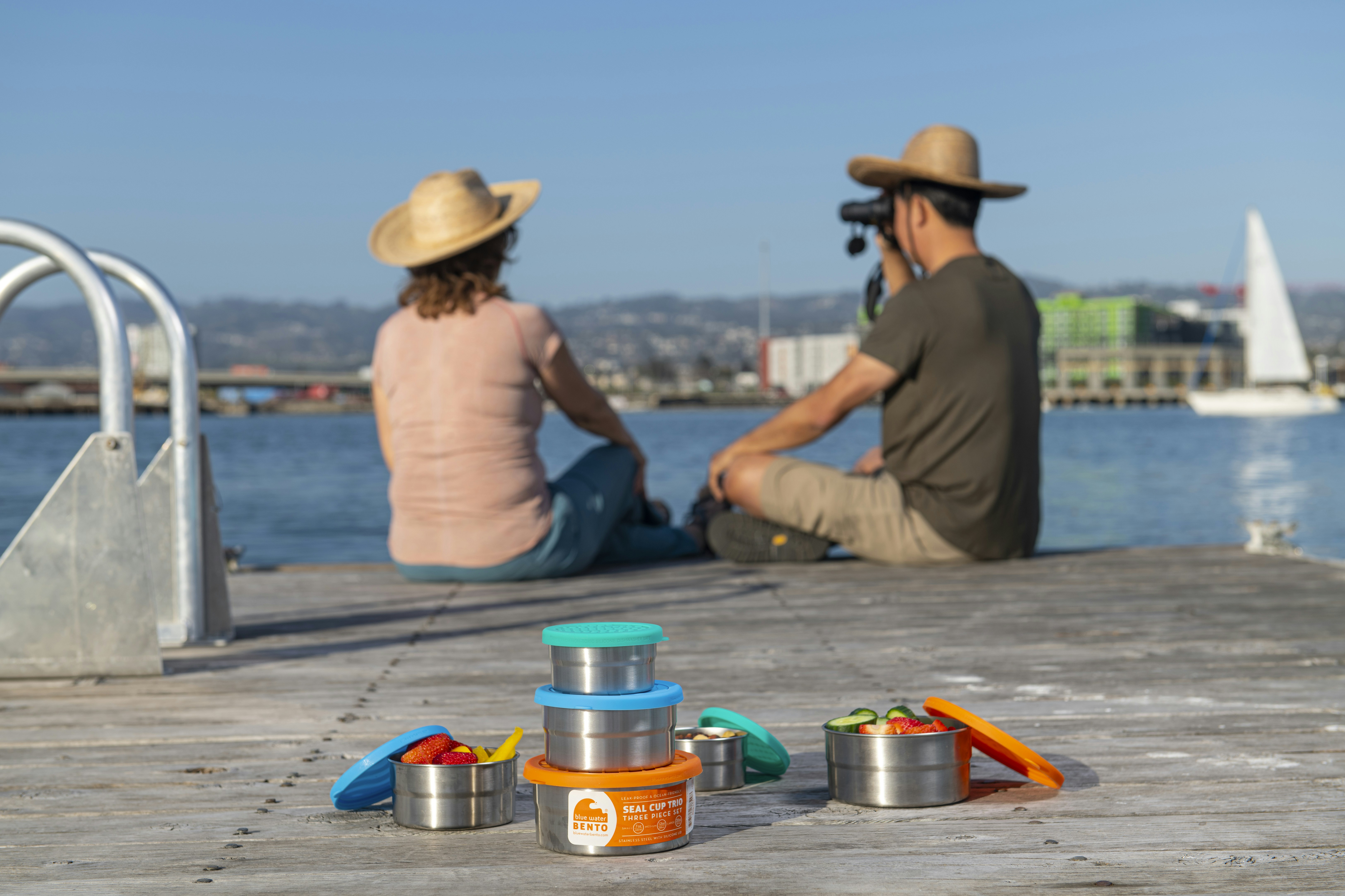 a couple of people sitting on a dock next to a body of water