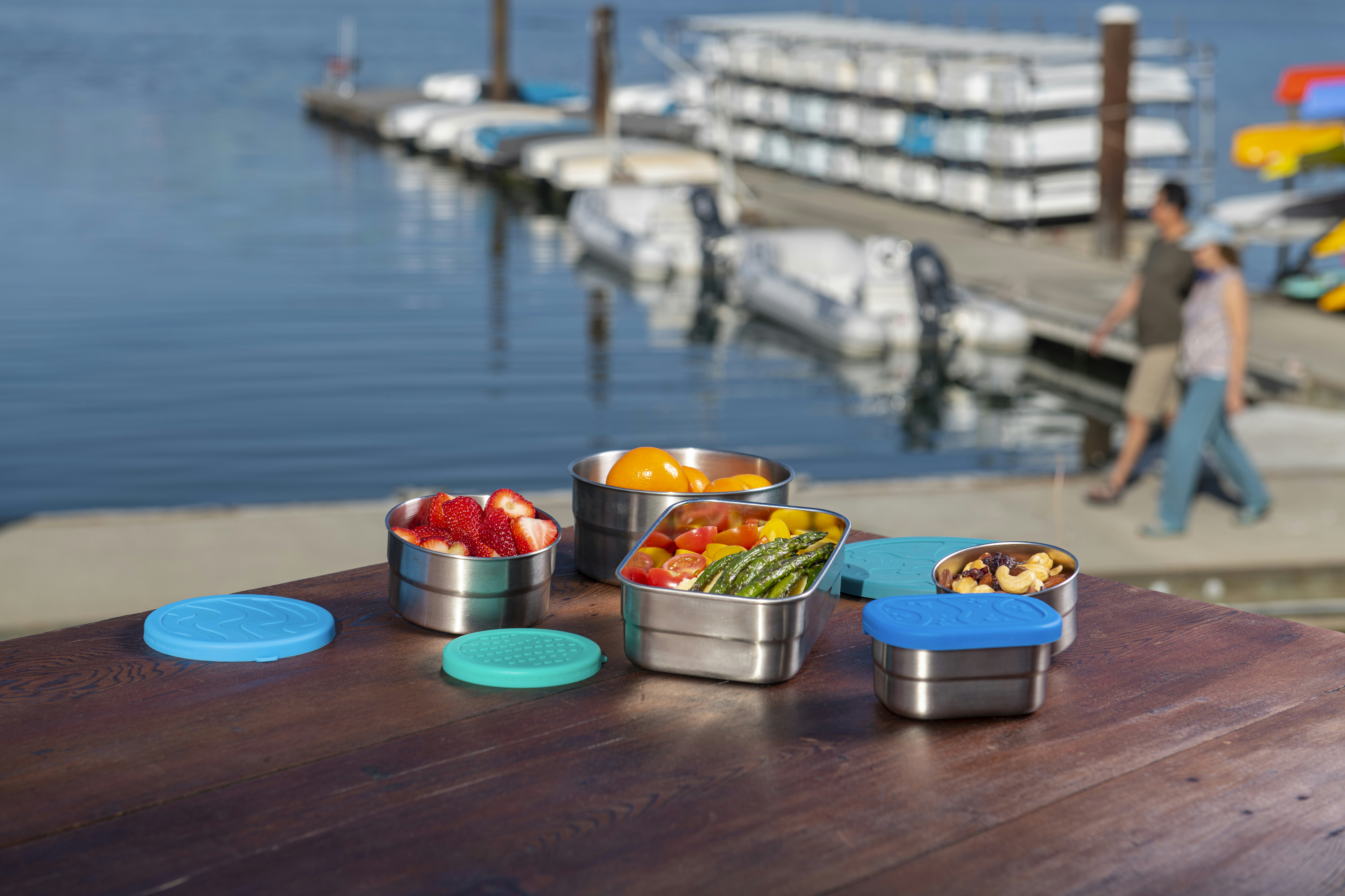 a wooden table topped with metal containers filled with fruit
