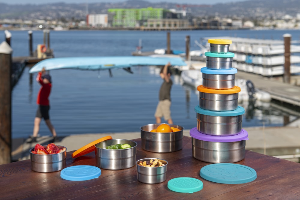 a wooden table topped with metal containers filled with food