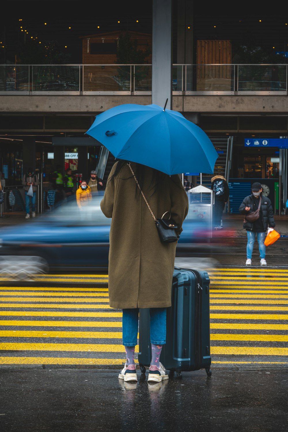 Eine Frau geht mit einem Regenschirm eine Straße entlang