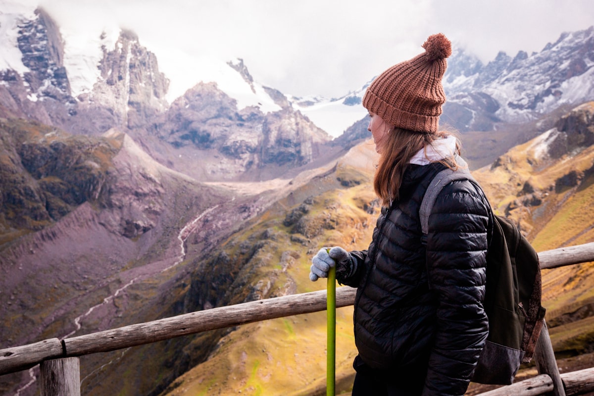 Woman standing on a wooden fence overlooking mountains