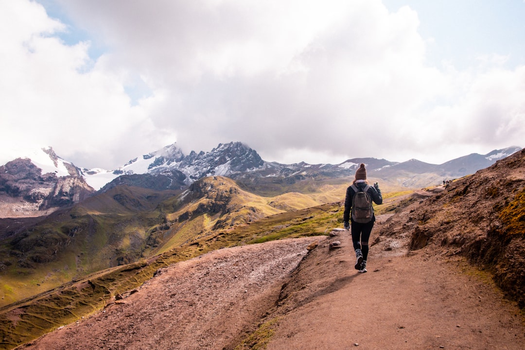 a person walking up a dirt path in the mountains,