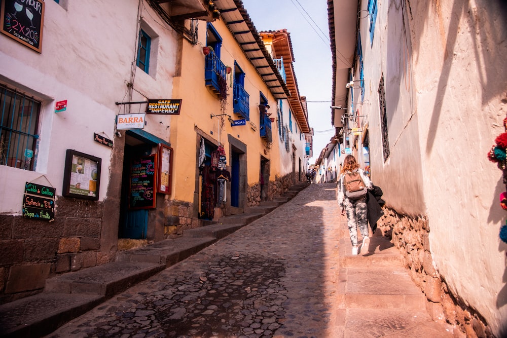 a woman walking down a street next to tall buildings