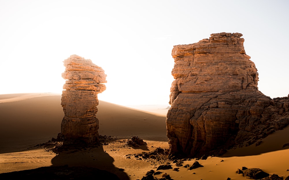 um par de grandes rochas sentadas no meio de um deserto
