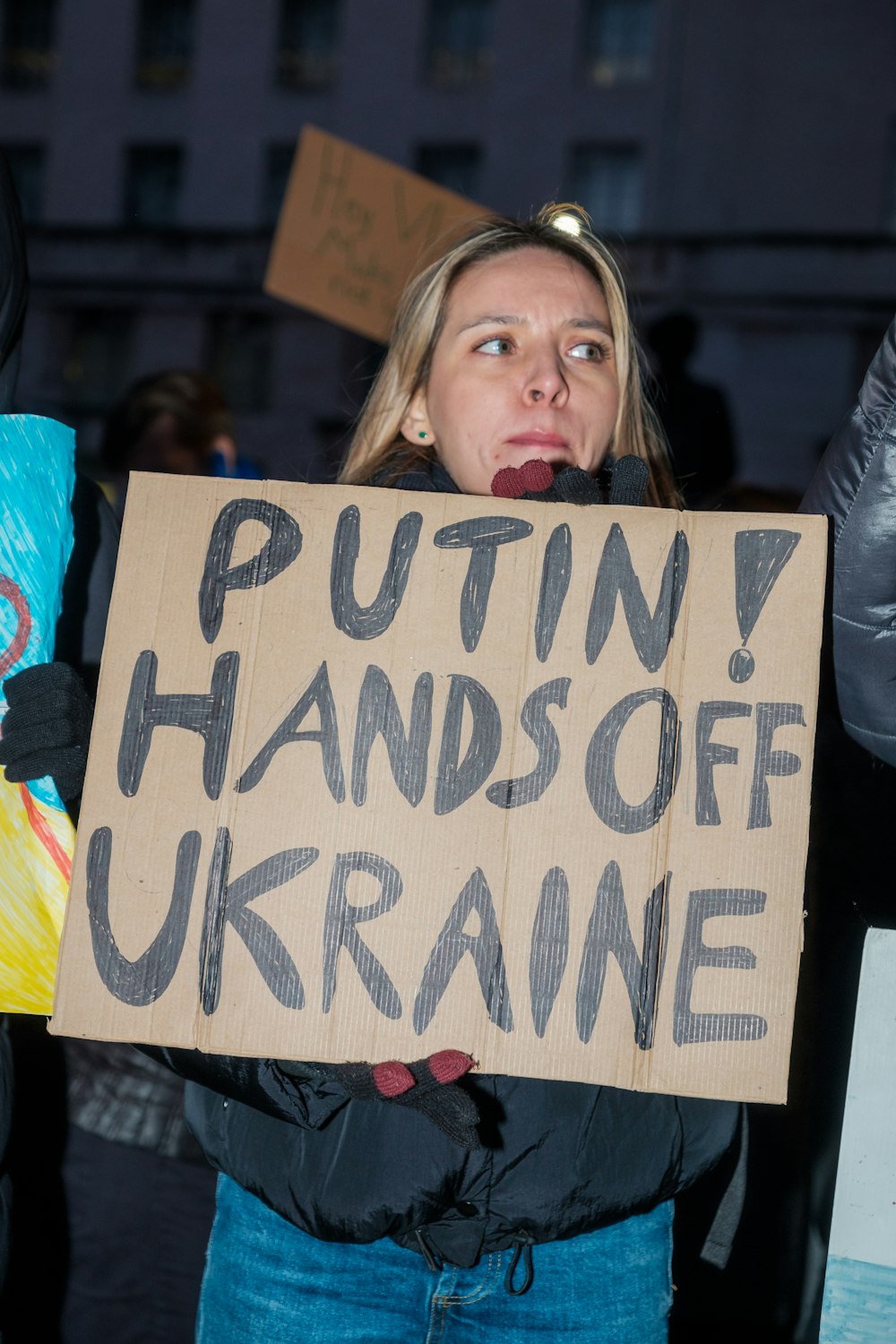a woman holding a sign that says puttin'hands off ukraine